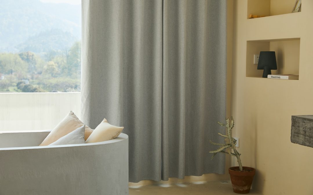 Grey electric curtains in a living room behind a sofa